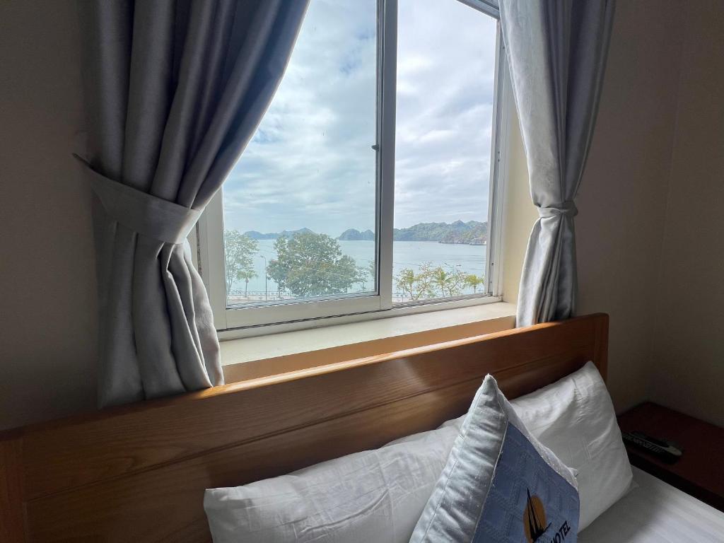 Schlafzimmer mit einem Fenster mit Blick auf das Wasser in der Unterkunft Làng Chài Hotel & Restaurant in Cát Bà