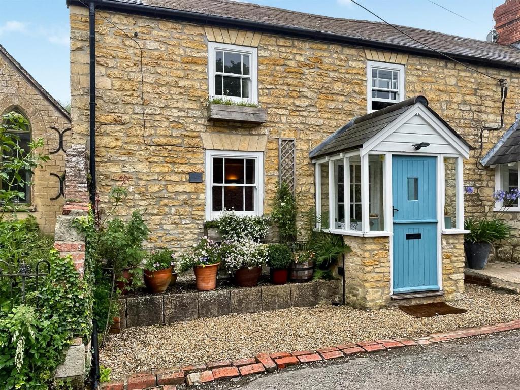 a brick house with a blue door and potted plants at Mill View Cottage in West Stour