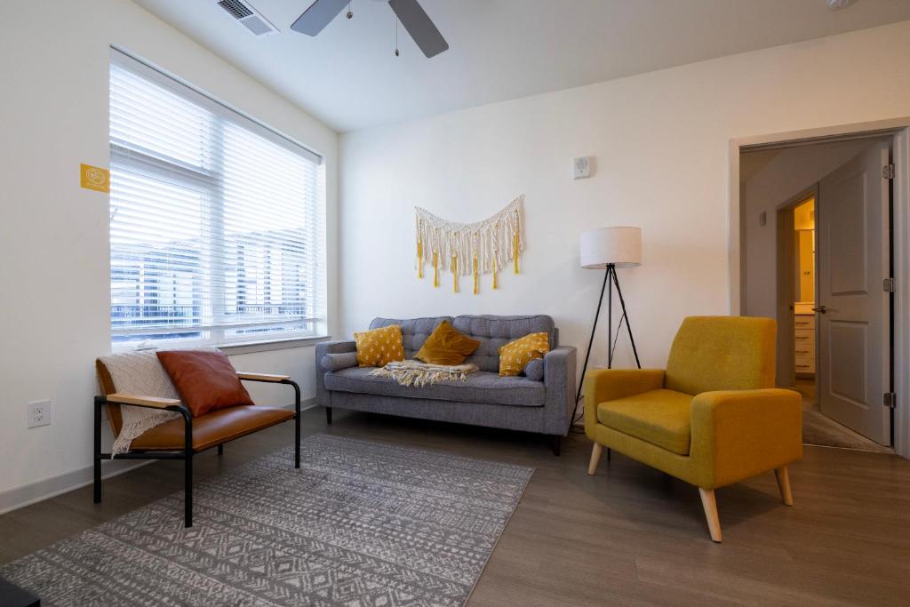 uma sala de estar com um sofá e duas cadeiras em Modern Nulu 2BR CozySuites 01 em Louisville