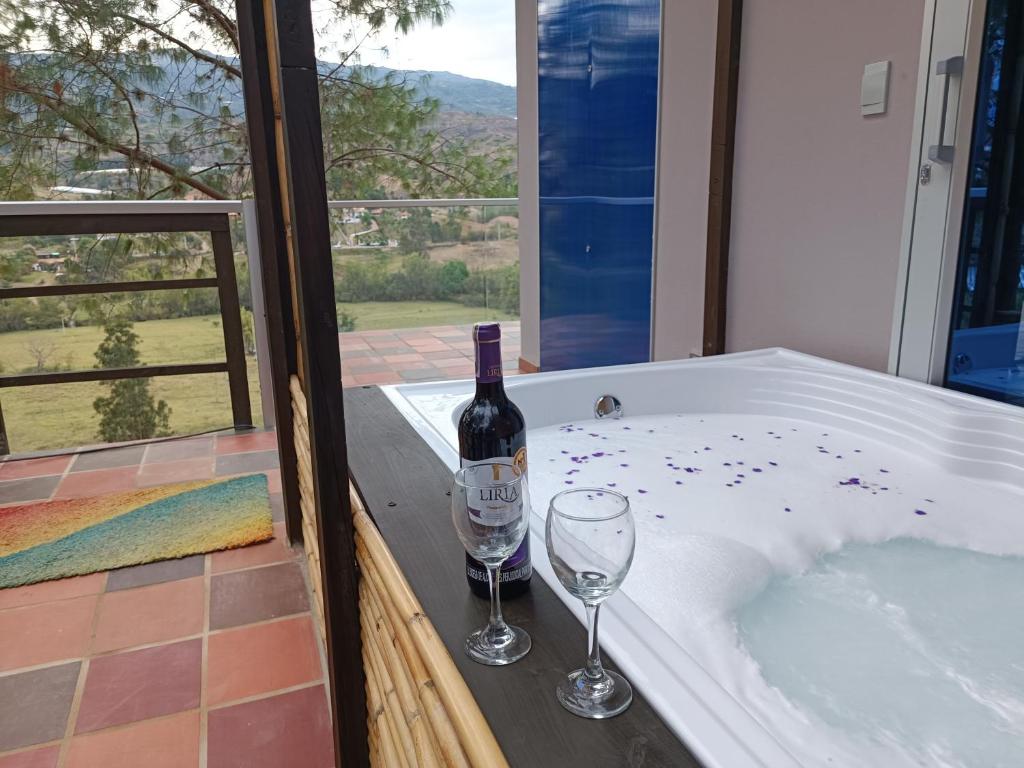Amonitas Glamping Deluxe في Tinjacá: زجاجة من النبيذ وكأسين على حوض الاستحمام