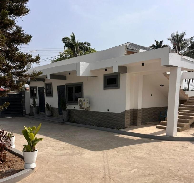 een wit huis met een paviljoen ervoor bij NBA PLUSH APARTMENT - NSROMA in Accra