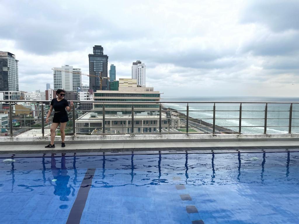 a woman standing next to a swimming pool on top of a building at In the heart of Colombo 2 Bedrooms Apartment in Colombo