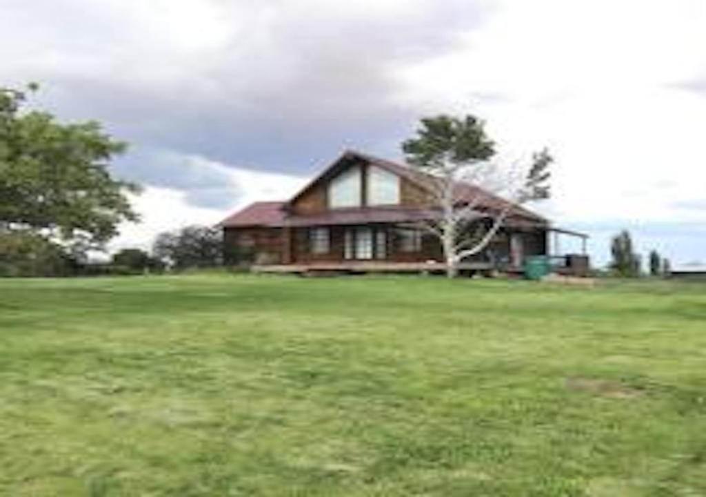 a house in a grassy field with a house at Log Haven in Blanding in Blanding