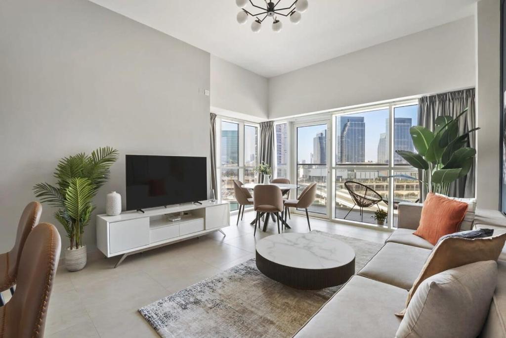 a living room with a television and a table with chairs at Silkhaus Al Reem island Modern 1BDR in Abu Dhabi