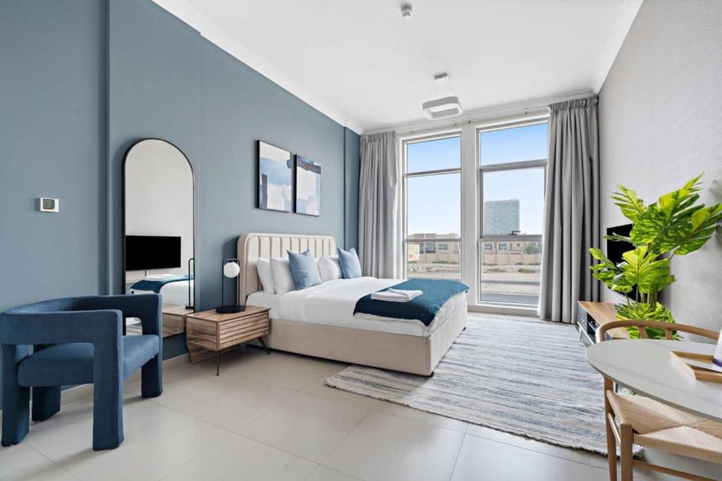 1 dormitorio con paredes azules, 1 cama y TV en Silkhaus new studio in Art Gardens pool access, en Dubái