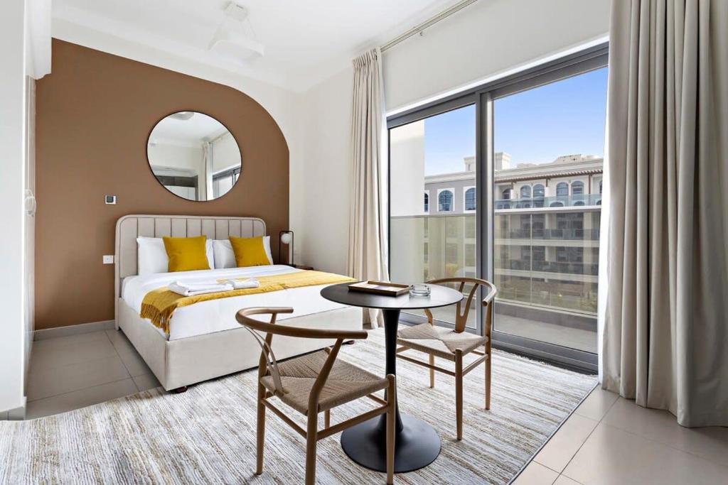 Schlafzimmer mit einem Bett, einem Tisch und einem Fenster in der Unterkunft Silkhaus aesthetic studio in Art Gardens with gym & pool access in Dubai