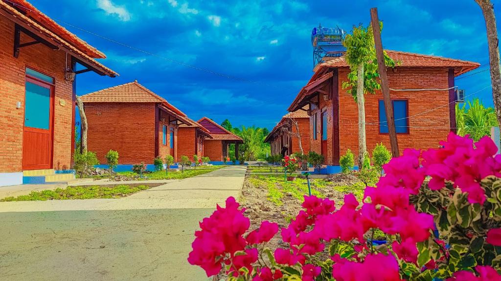 eine Reihe von Häusern mit rosa Blumen im Vordergrund in der Unterkunft HOMESTAY HƯƠNG RỪNG in Tân Phú
