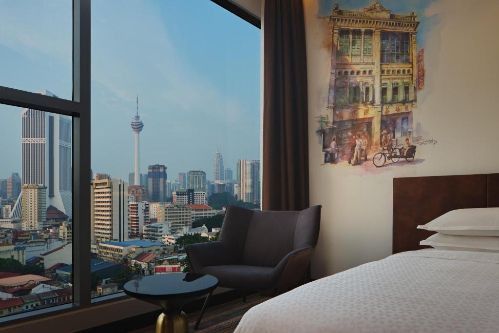 a bedroom with a bed and a chair and a window at Four Points by Sheraton Kuala Lumpur, Chinatown in Kuala Lumpur
