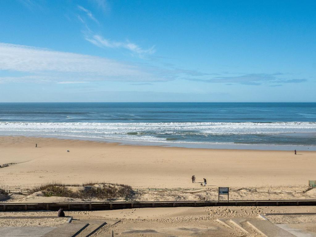 una spiaggia con persone che camminano sulla sabbia e sull'oceano di Appartement 6 personnes à Mimizan avec parking, balcon et local à vélos - FR-1-50-126 a Mimizan