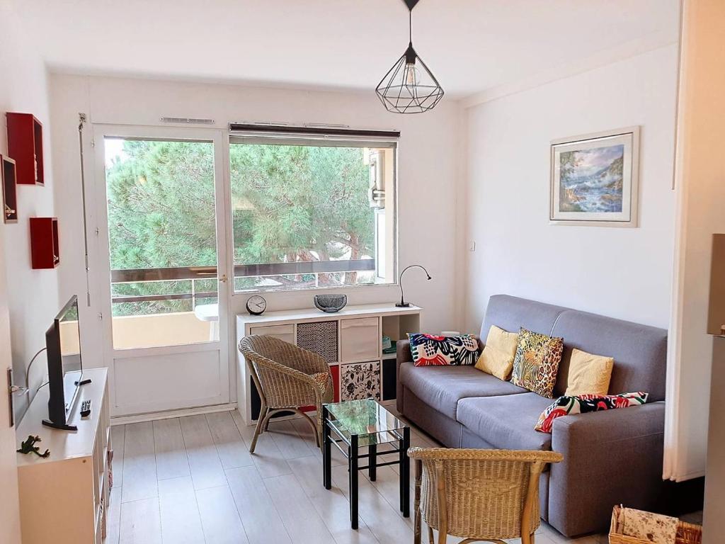 ein Wohnzimmer mit einer Couch und einem Fenster in der Unterkunft T2 climatisé 3* avec Loggia, Parking sécurisé, WiFi, proche plage - Bormes-les-Mimosas - FR-1-610-98 in Bormes-les-Mimosas