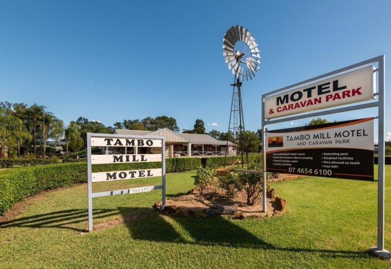 dos señales frente a un motel y un molino de viento en Tambo Mill Motel & Caravan Park, en Tambo