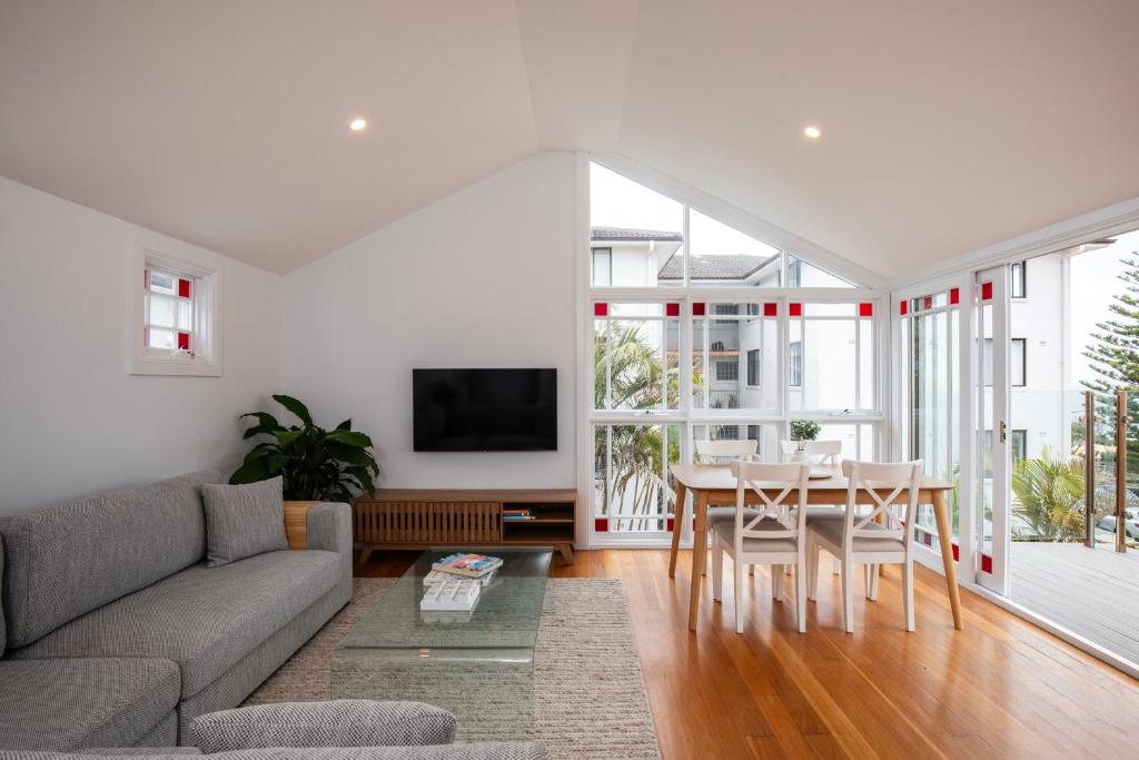 ein Wohnzimmer mit einem Sofa und einem Tisch in der Unterkunft Seaside apartment, 100m to beach in Narrabeen
