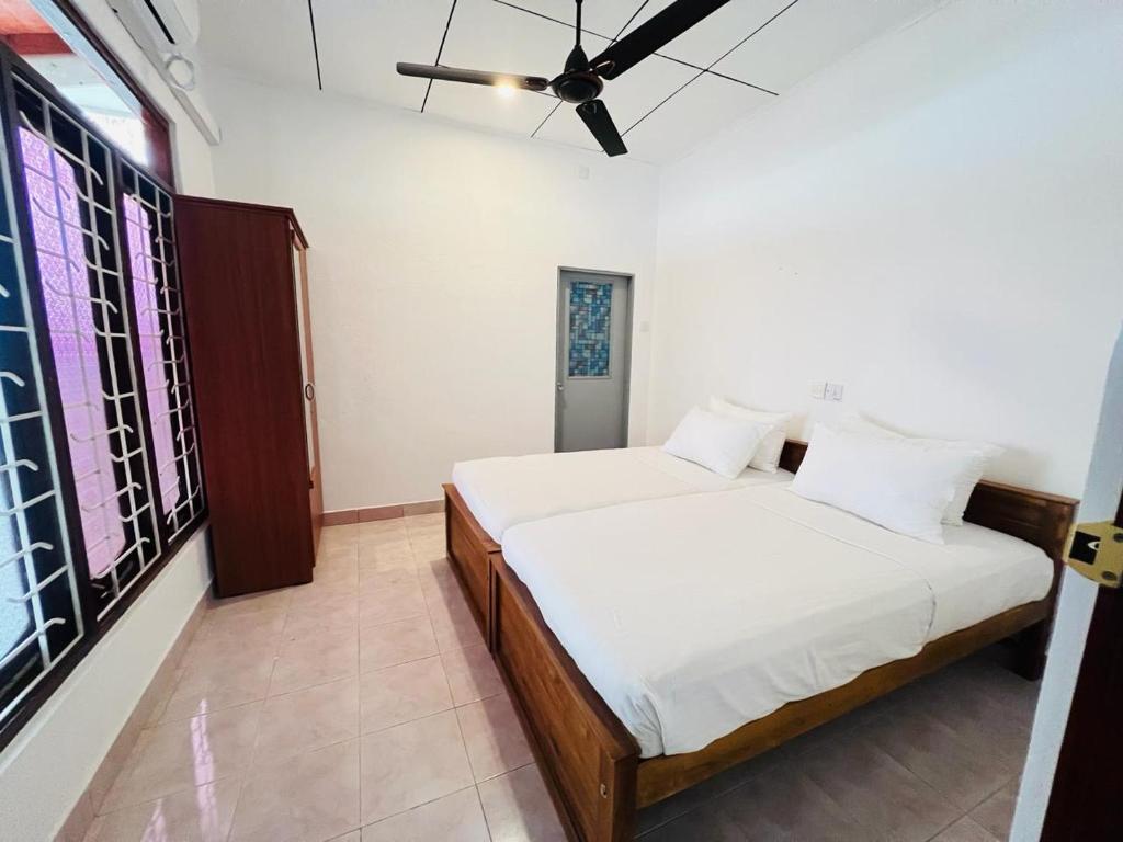a bedroom with two beds and a ceiling fan at Bungalow By Tropical Villa in Weligama