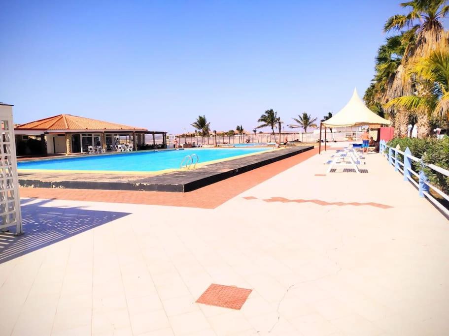 a large swimming pool with chairs and a umbrella at Feeling Cabo Verde in Beirona