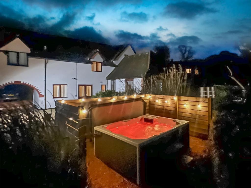 una bañera de hidromasaje en el patio de una casa por la noche en Dartmoor View en Stoke Gabriel