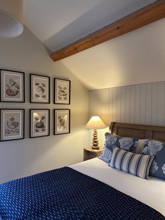 a bedroom with a blue bed and framed pictures on the wall at The Red Lion Inn Alnmouth in Alnmouth