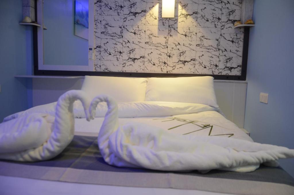 una cama con dos almohadas en forma de cisne en Isle inn {Fuvahmulah), en Fuvahmulah