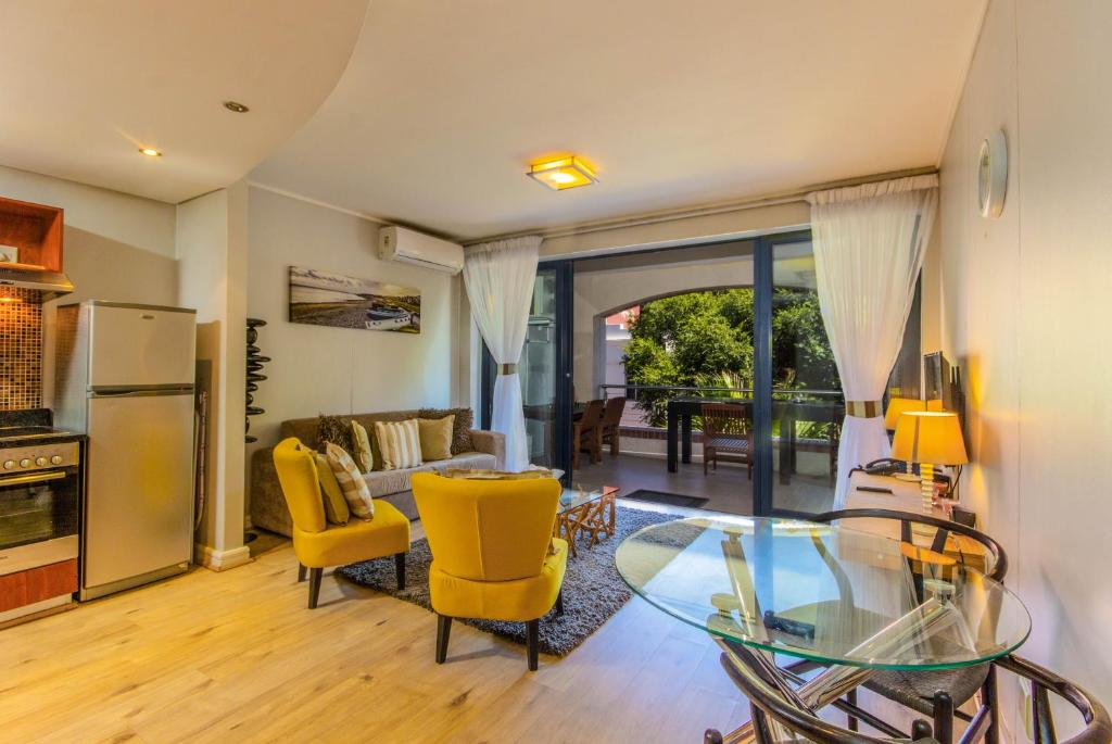 salon ze szklanym stołem i żółtymi krzesłami w obiekcie One Bedroom With Private Balcony w Kapsztadzie