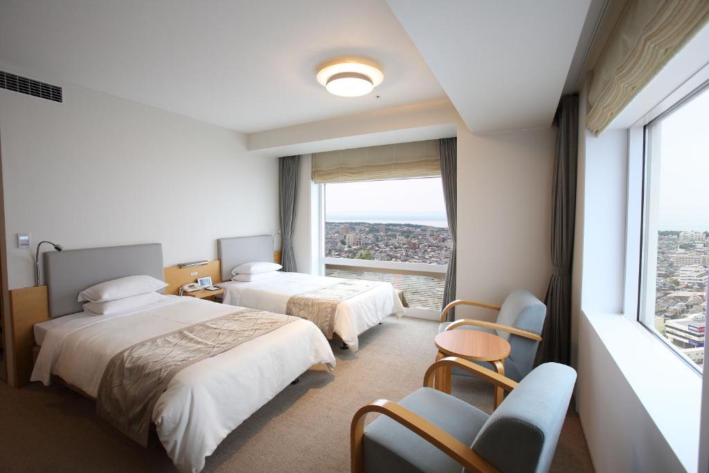 a hotel room with two beds and a large window at Hotel Nikko Niigata in Niigata