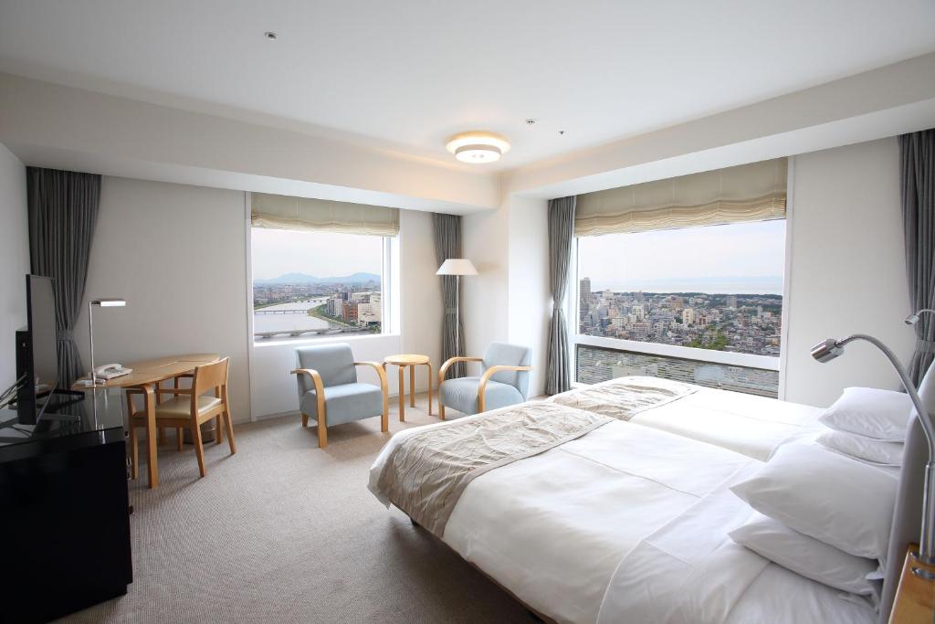 a hotel room with a bed and a table and chairs at Hotel Nikko Niigata in Niigata