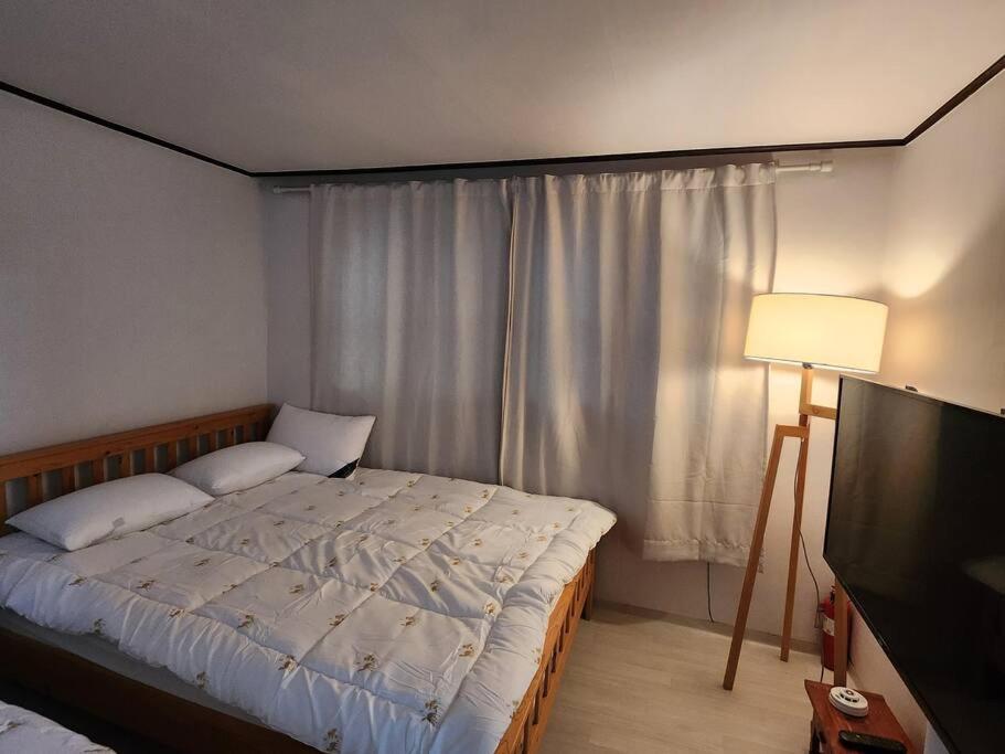 sypialnia z łóżkiem, lampką i telewizorem w obiekcie Yeongdeungpo Windsor w Seulu