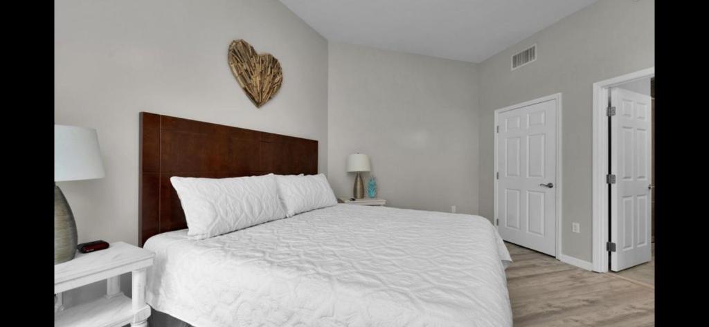 ein Schlafzimmer mit einem weißen Bett mit einem hölzernen Kopfteil in der Unterkunft The Palms of Destin-2116 in Destin