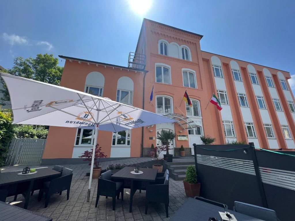 a restaurant with tables and an umbrella in front of a building at Hotel Am Mühlenteich in Schwelm