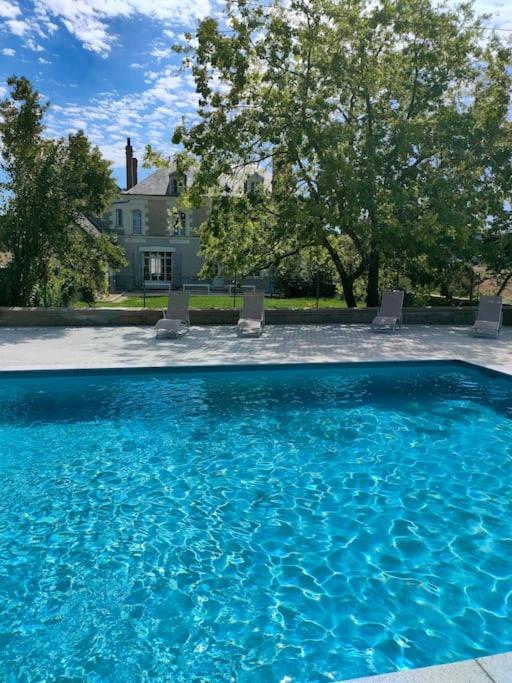 - une piscine avec des chaises en face d'une maison dans l'établissement Le Domaine du Bas Guéret, à Mareuil-sur-Cher