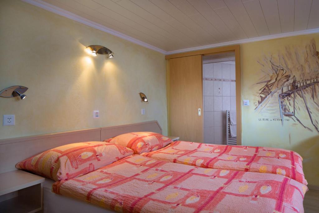 una camera con letto e piumone rosa di Relais de la Sarvaz a Saillon