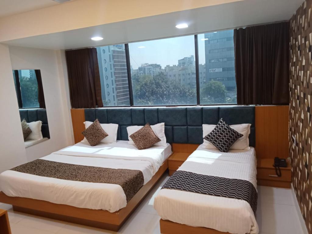 アーメダバードにあるHotel Exoticの大きな窓付きの客室で、ベッド2台が備わります。
