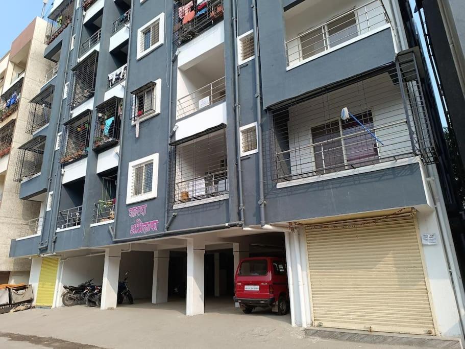 a blue building with a red van parked in front of it at 2BHK AC Service Apartment 101 Manjari in Pune