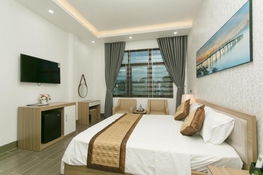 Bảo Ngọc Hotel في Uông Bí: غرفة فندقية بسرير وتلفزيون بشاشة مسطحة