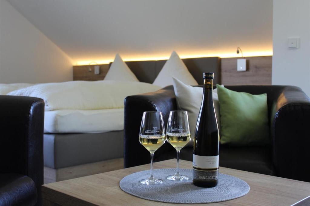 uma garrafa de vinho e dois copos de vinho numa mesa em Ferienweingut Hansjosten em Longuich