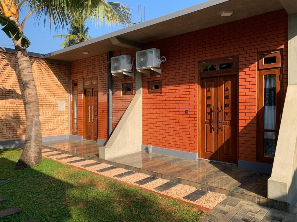 a brick building with brown doors and a palm tree at Airport Colombo Pocket Paradise in Seeduwa