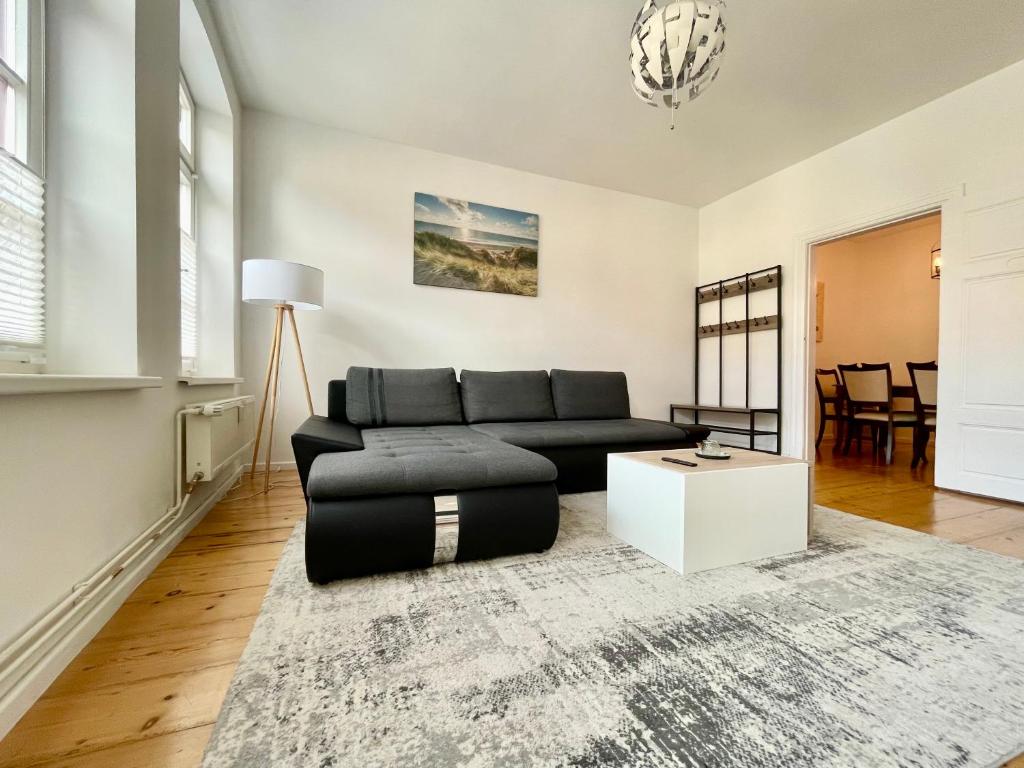 uma sala de estar com um sofá preto e uma mesa em FeWo Meeres Luft em Wismar