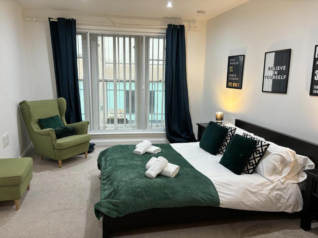 um quarto com uma cama grande e uma cadeira verde em Apartment in the heart of Cardiff City Centre em Cardiff