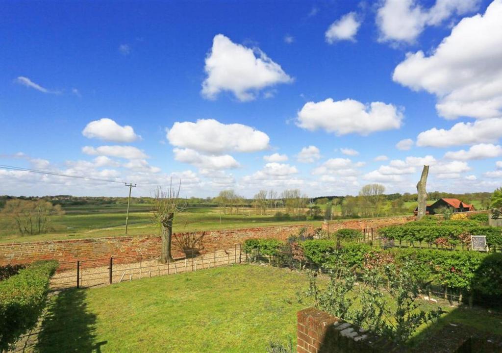 a garden with a fence and a field of crops at Meadow House in Blythburgh