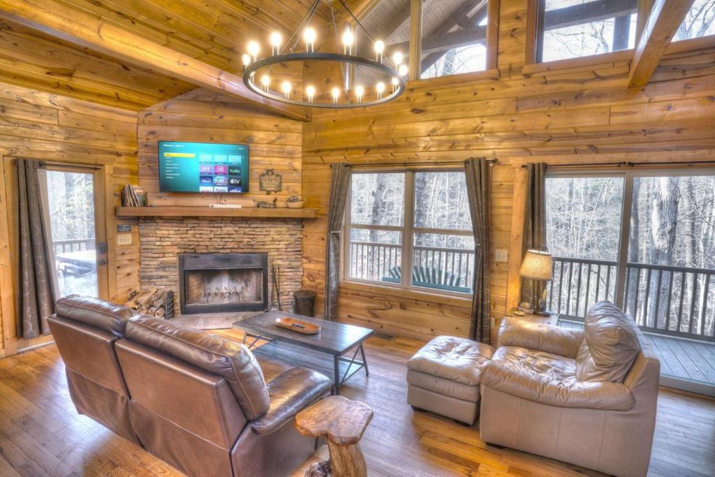 uma sala de estar com mobiliário de couro e uma lareira em Luxury Cabin Sleeps 8 with creekside fire pit near Helen GA em Cleveland