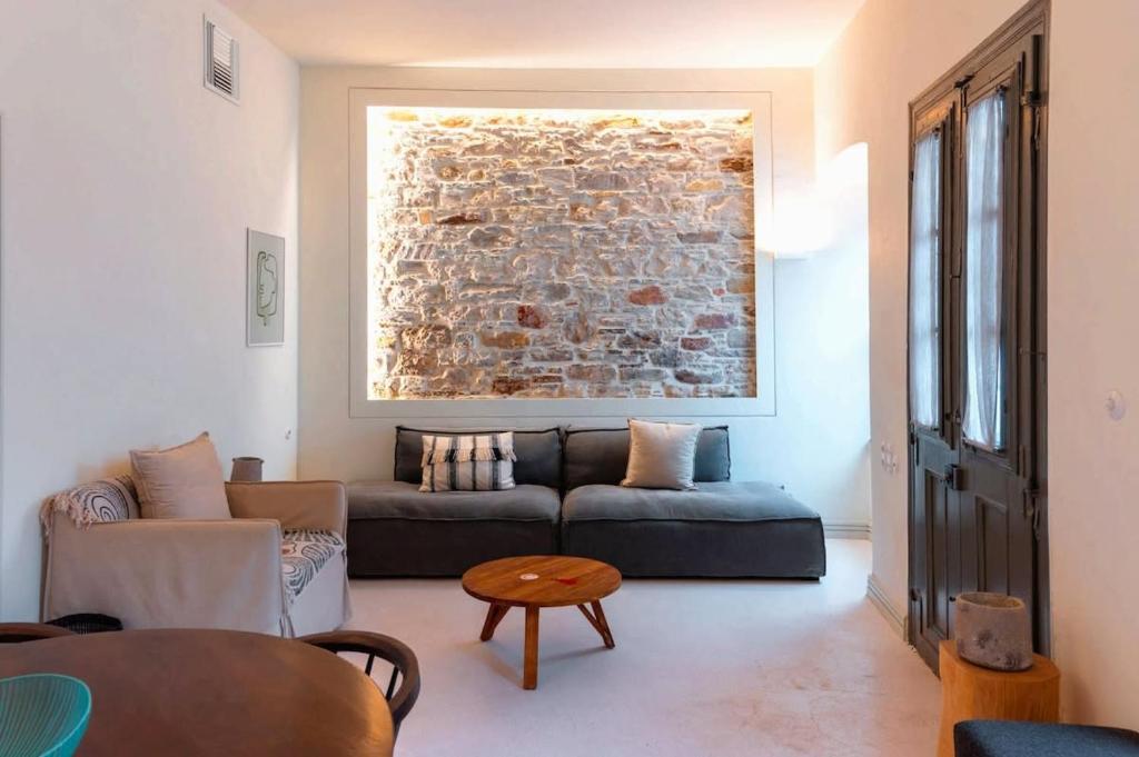 a living room with a couch and a brick wall at Samos Serenity - Classic Retreat near the beach in Koumeika