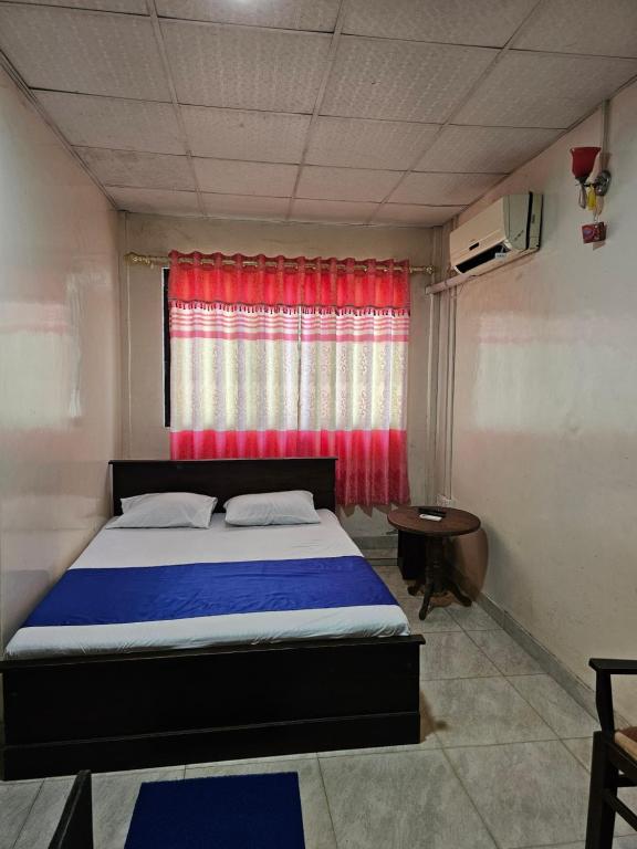 Hotel SELLA & Rest في Kilinochchi: غرفة نوم بسرير وستارة حمراء