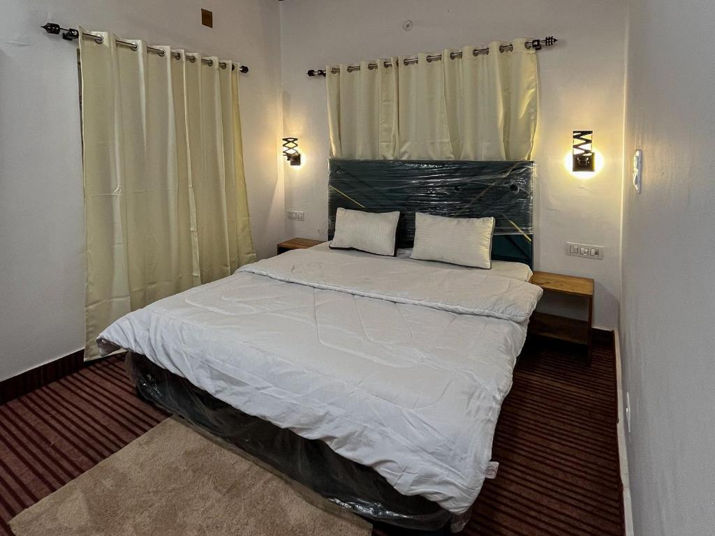 una camera da letto con un grande letto bianco con due cuscini di The Sunrise Villa Homestay a Rishikesh