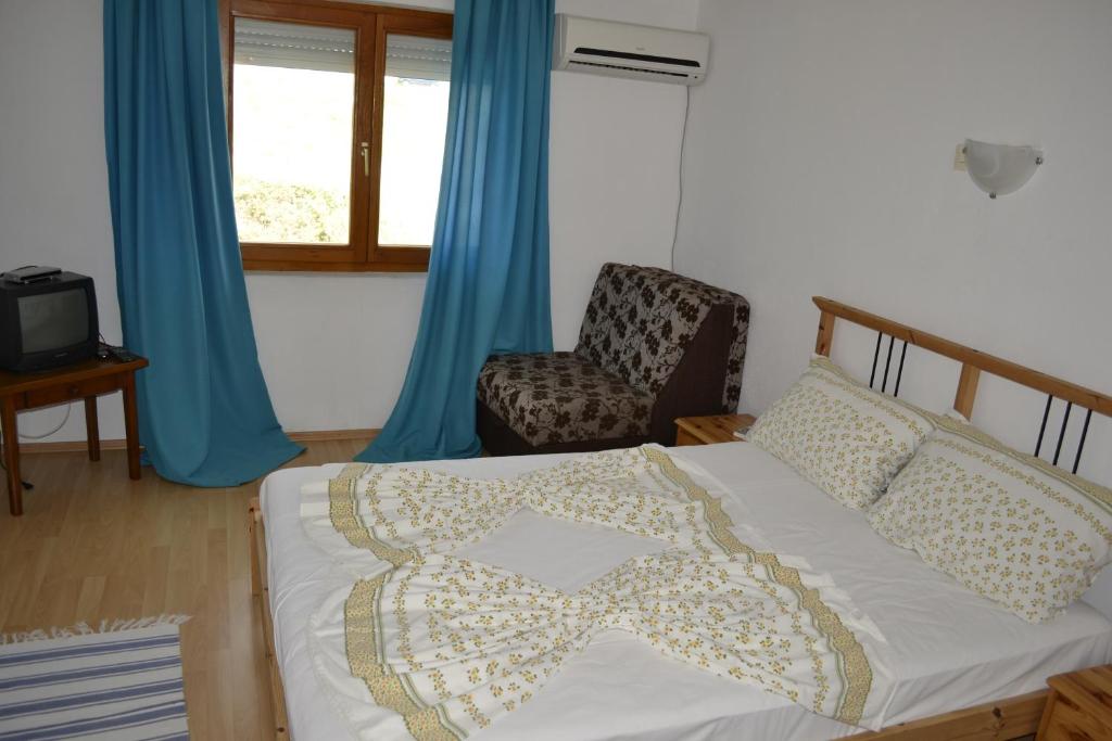a bedroom with a bed and a chair and a window at Guest House Morski val in Bar