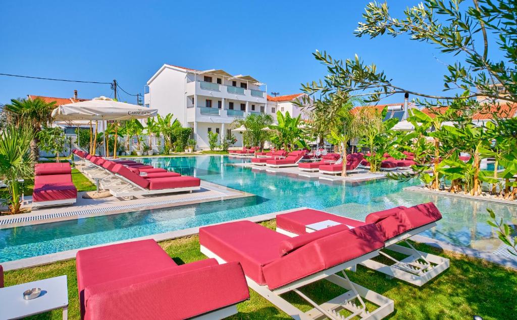una piscina con tumbonas rojas en un complejo en Èmar Corfu, en Arillas
