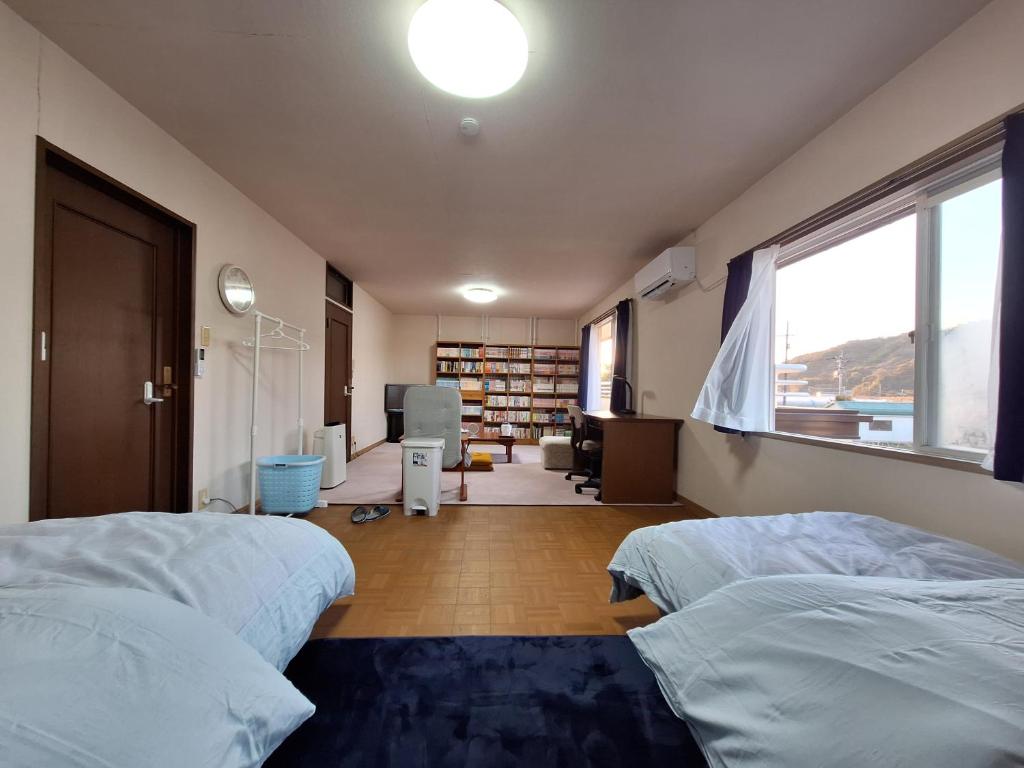 a large room with two beds and a window at guesthouse ONAKA in Mimase