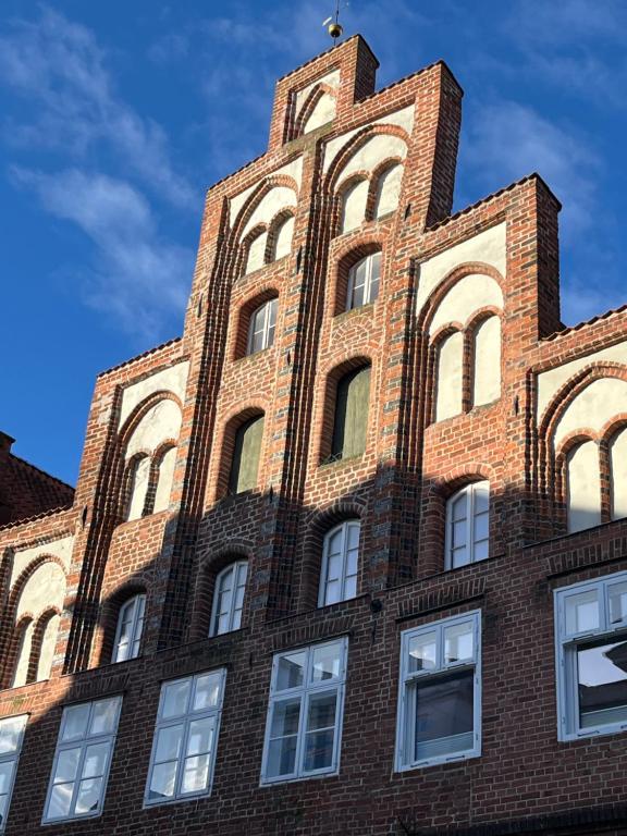 ein hohes rotes Backsteingebäude mit weißen Fenstern in der Unterkunft Lüneburg Zentral in Lüneburg