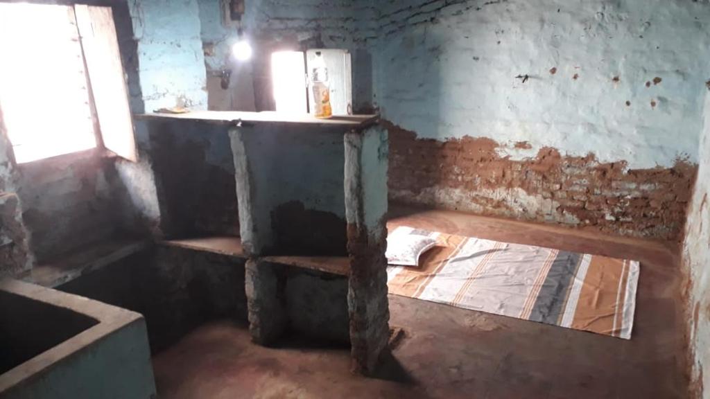 um quarto antigo com um frigorífico e uma mesa em Mud House em Miraj