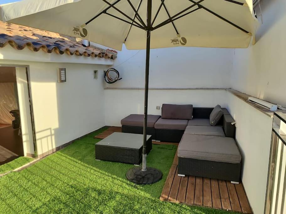 a patio with a couch and an umbrella at Ca La Perla in Albalat de Taronchers