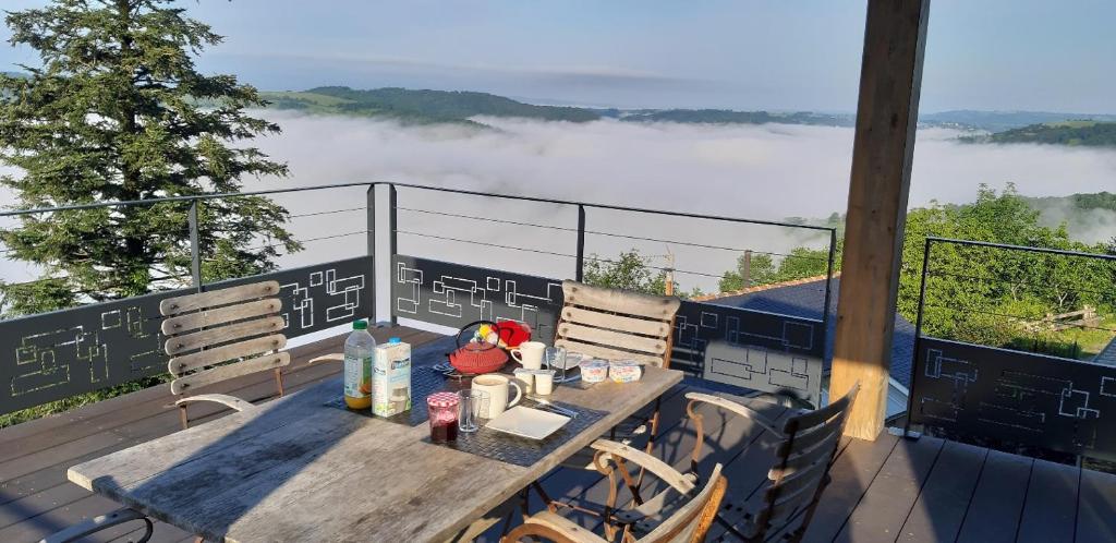 a table and chairs on a balcony with a view of clouds at Louradou-sur-Ciel in Jouqueviel