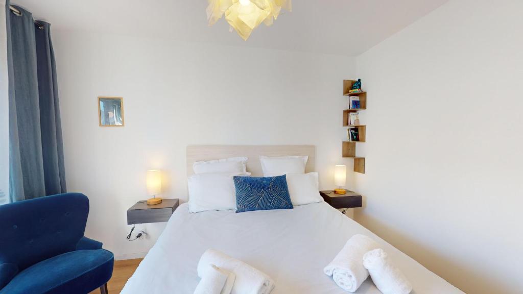 een slaapkamer met een wit bed en een blauwe stoel bij CityHeart Constellation avec parking in Straatsburg