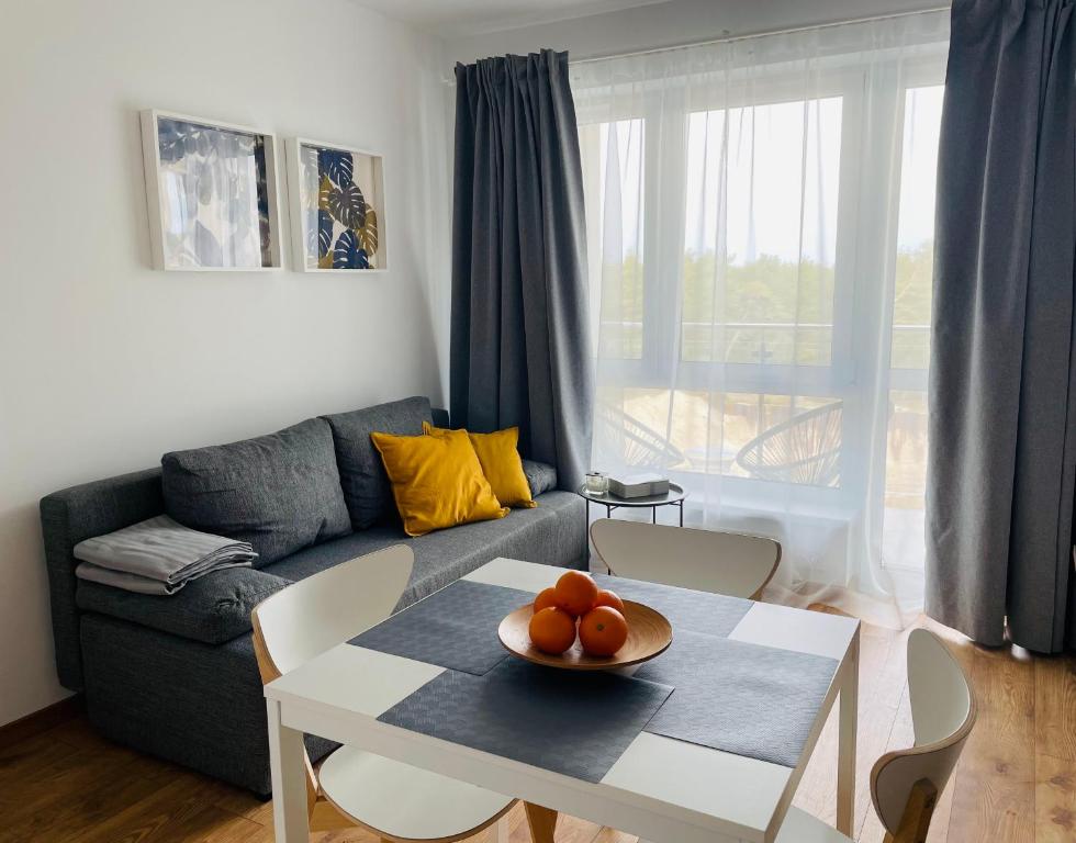 a living room with a couch and a table with oranges on it at Apartament Foka - Rowy in Rowy